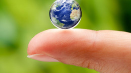 Finger with water droplet containing the world